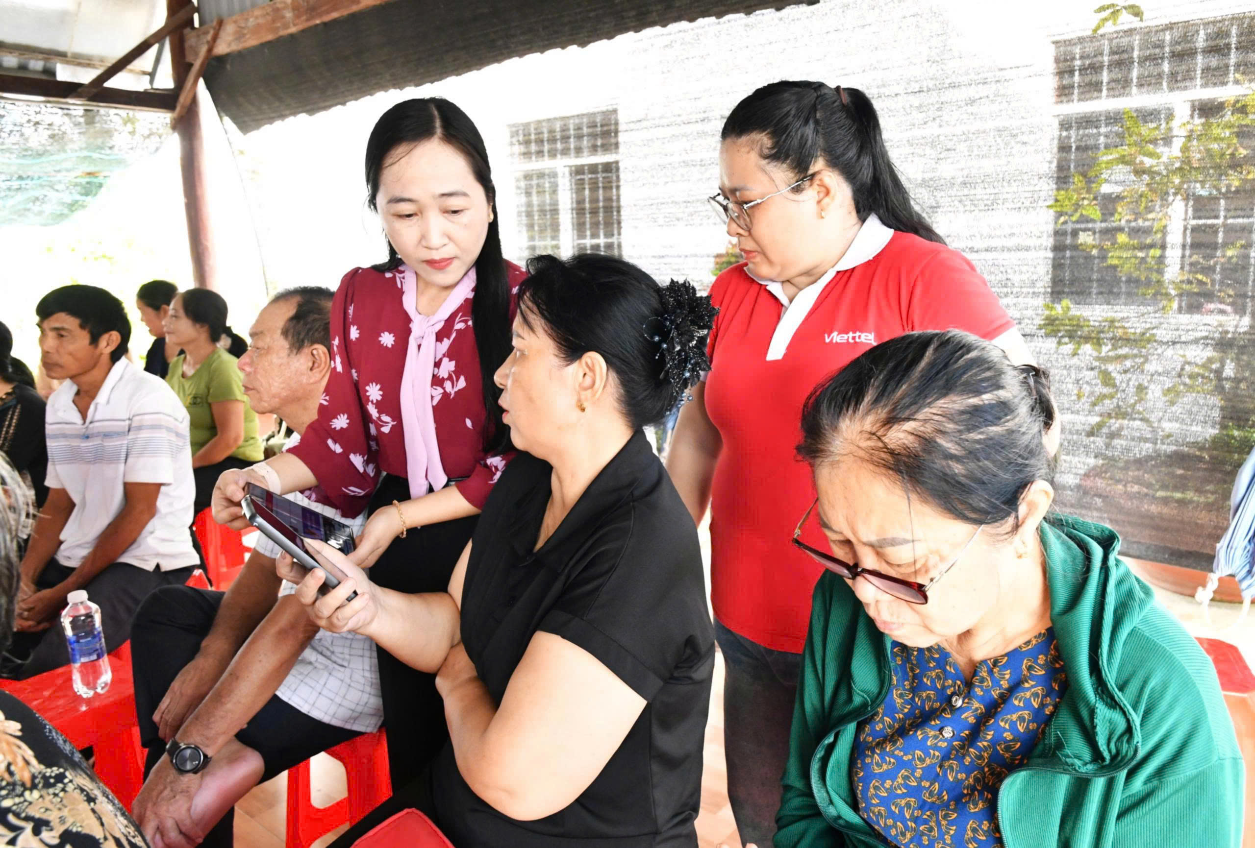 Ảnh 2: Công chức phòng Văn hóa – Xã hội xã Hòn Đất hướng dẫn người dân thao tác trên ứng dụng VNeID