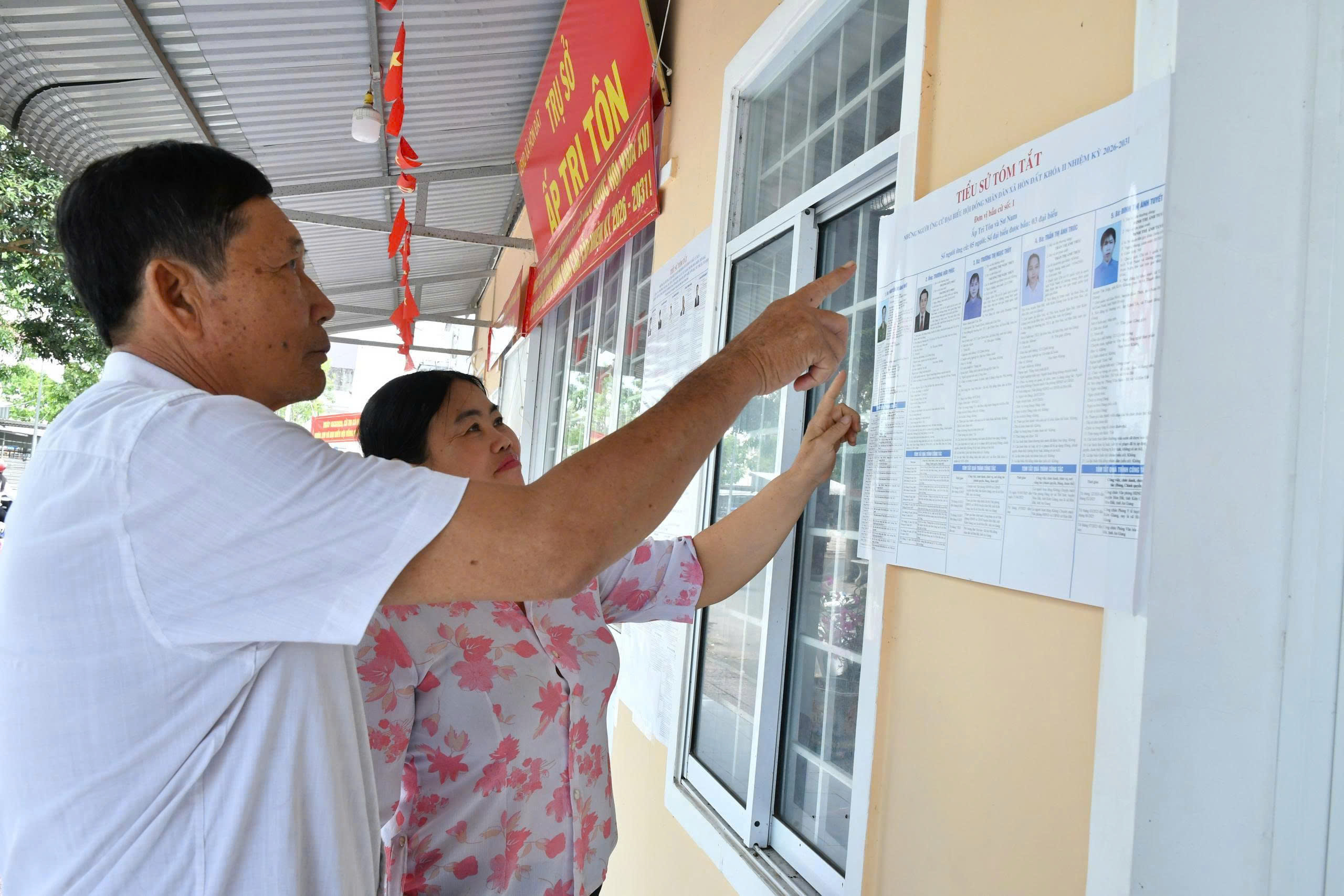 Ảnh 3: Cử tri Trần Kim Ủ, ấp Tri Tôn đang xem danh sách người ứng cử được niêm yết công khai tại tru sở ấp