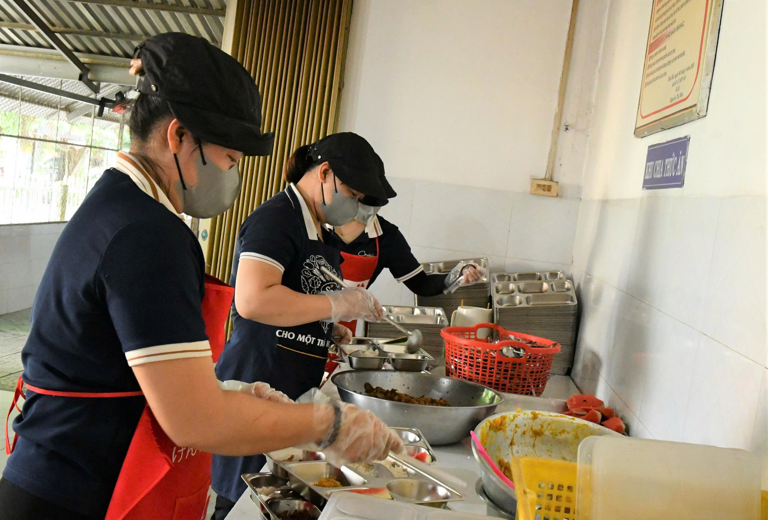 Ảnh 2: Nhân viên biếp ăn bán trú Trường tiểu học TTHĐ 1 đang chuẩn bị các suất ăn cho học sinh.