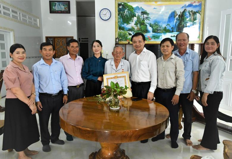 Bí thư Đảng ủy xã Hòn Đất Dương Minh Tâm trao huy hiệu đảng và tặng hoa chúc mừng đảng viên Giang Văn Lịch